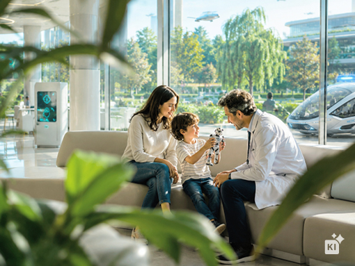 Woman and a child sitting next to a man with a lab coat, showing a toy with slightly blurry plants in the front.
