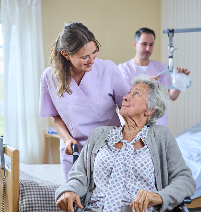 A female nurse and an elderly woman sitting in wheelchair looking at each other